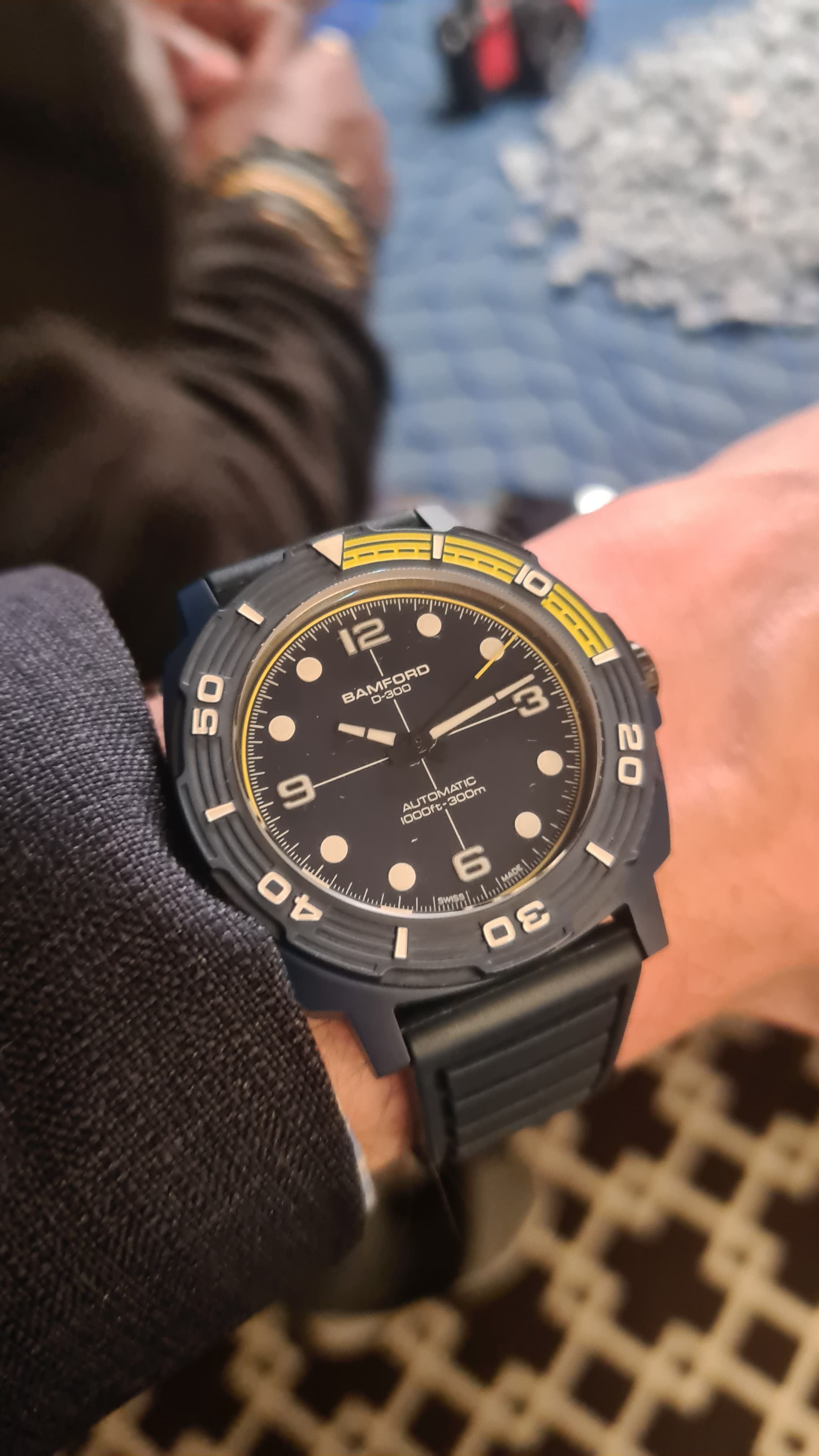 a dark blue ceramic dive watch from bamford with yellow and white numerals