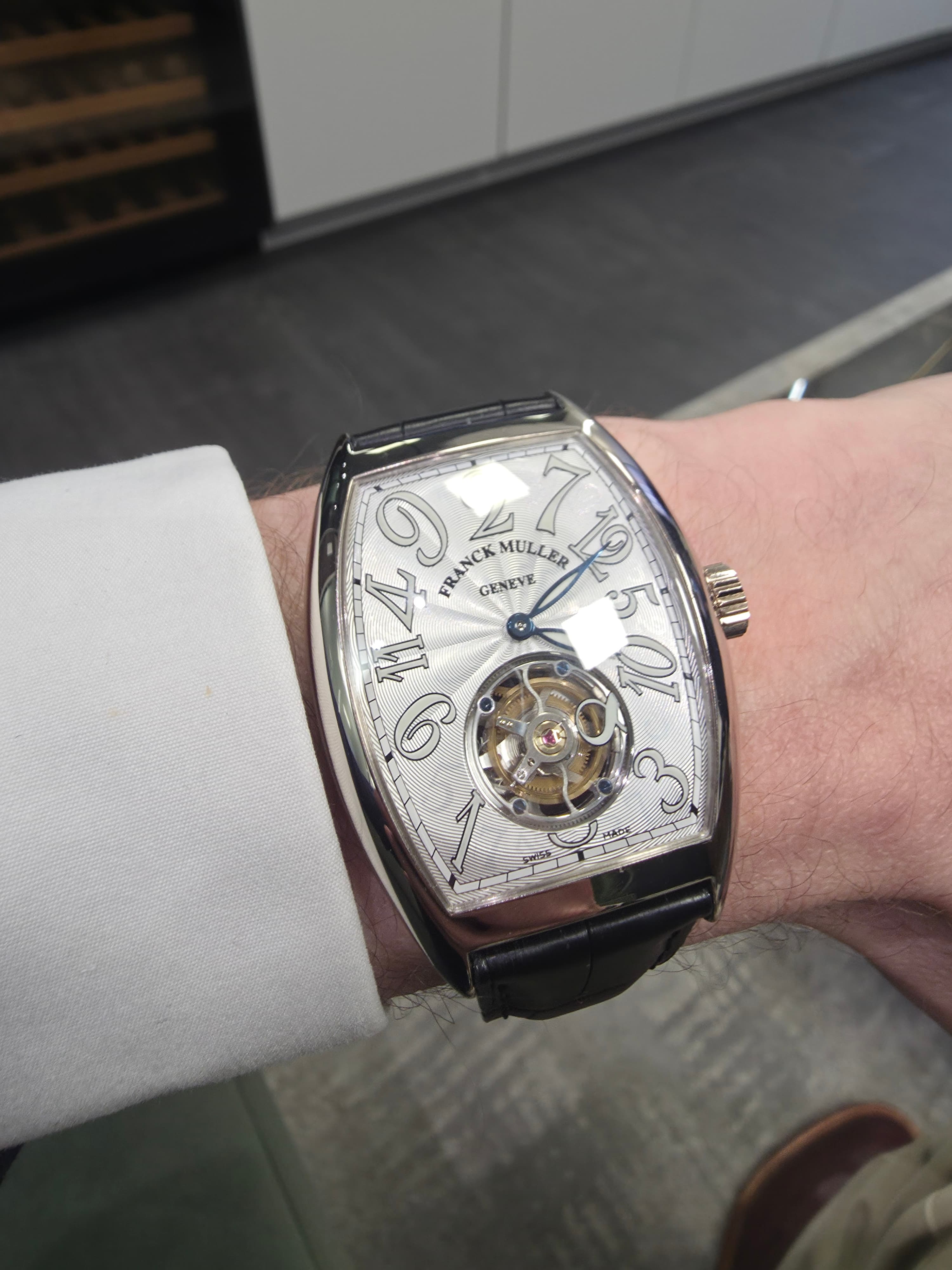 a tonneau shaped frank mueller crazy hours tourbillon watch in platinum with a silver guilloche dial