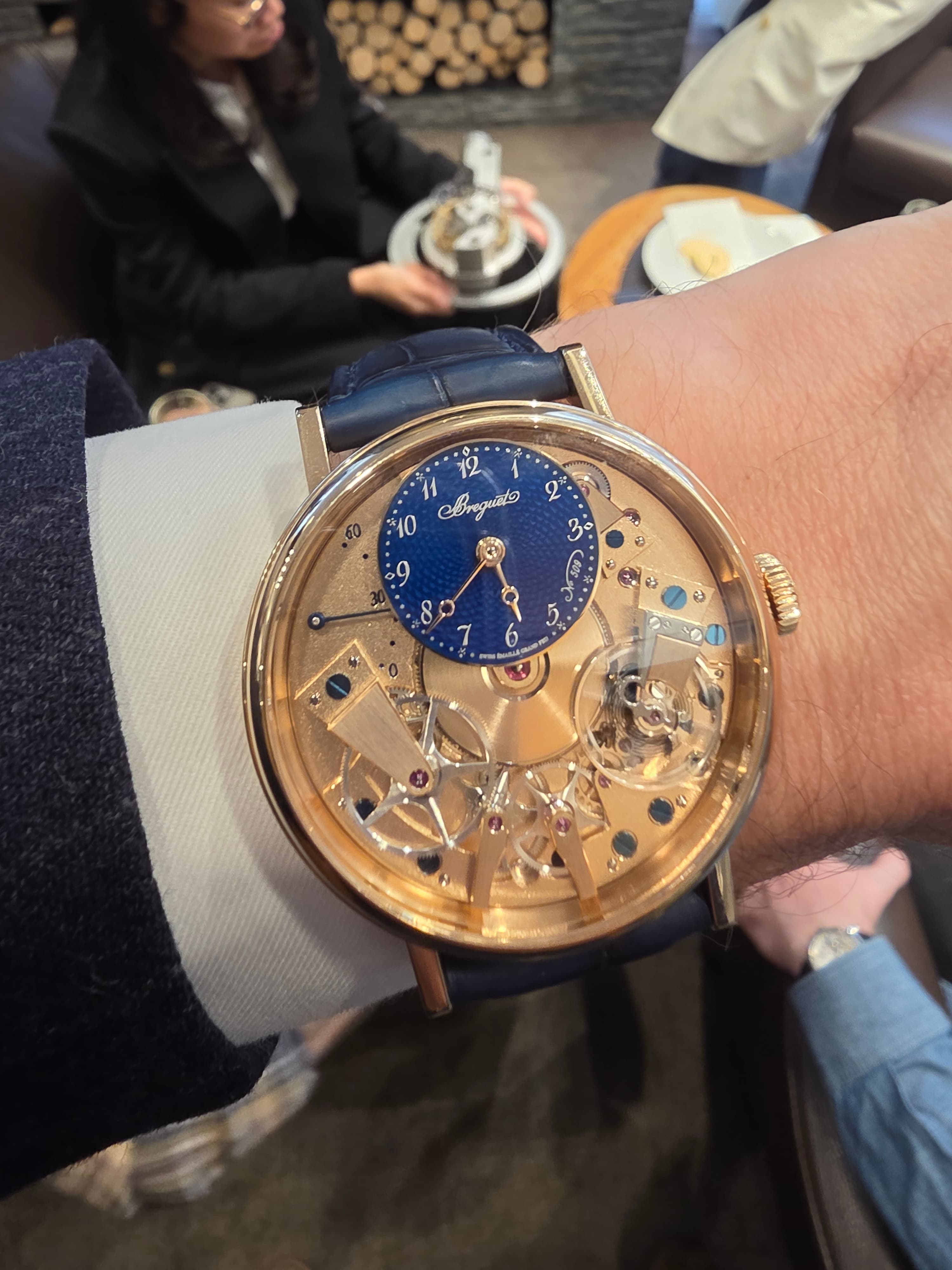 a gold Breguet watch with the movement parts visible and all the base plate polished with a small dial at 12 o'clock with blue enamel and guilloche engraving