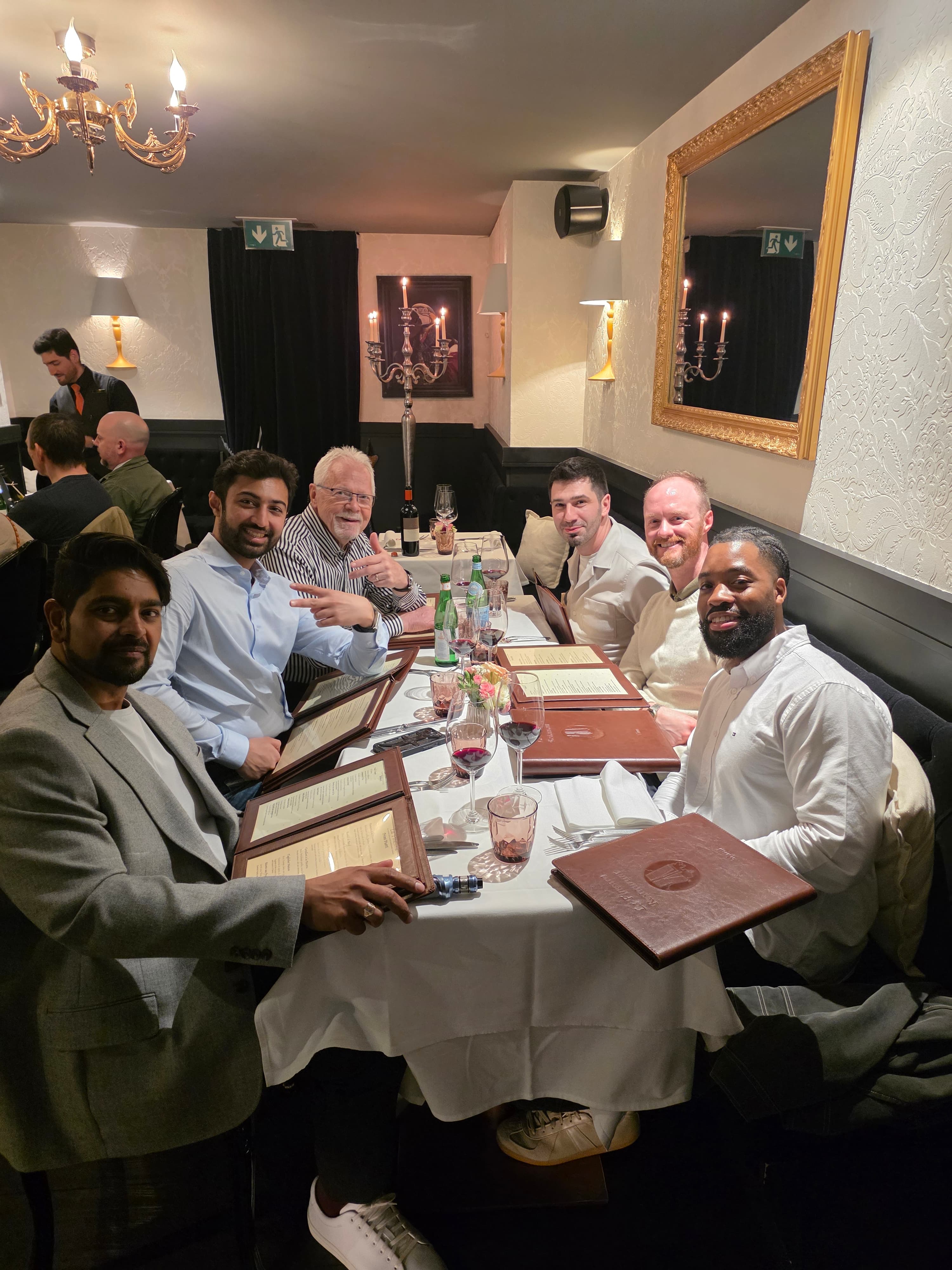dinner tbale wth six guys with menus wine and mirror on the wall in La Finestre Geneva