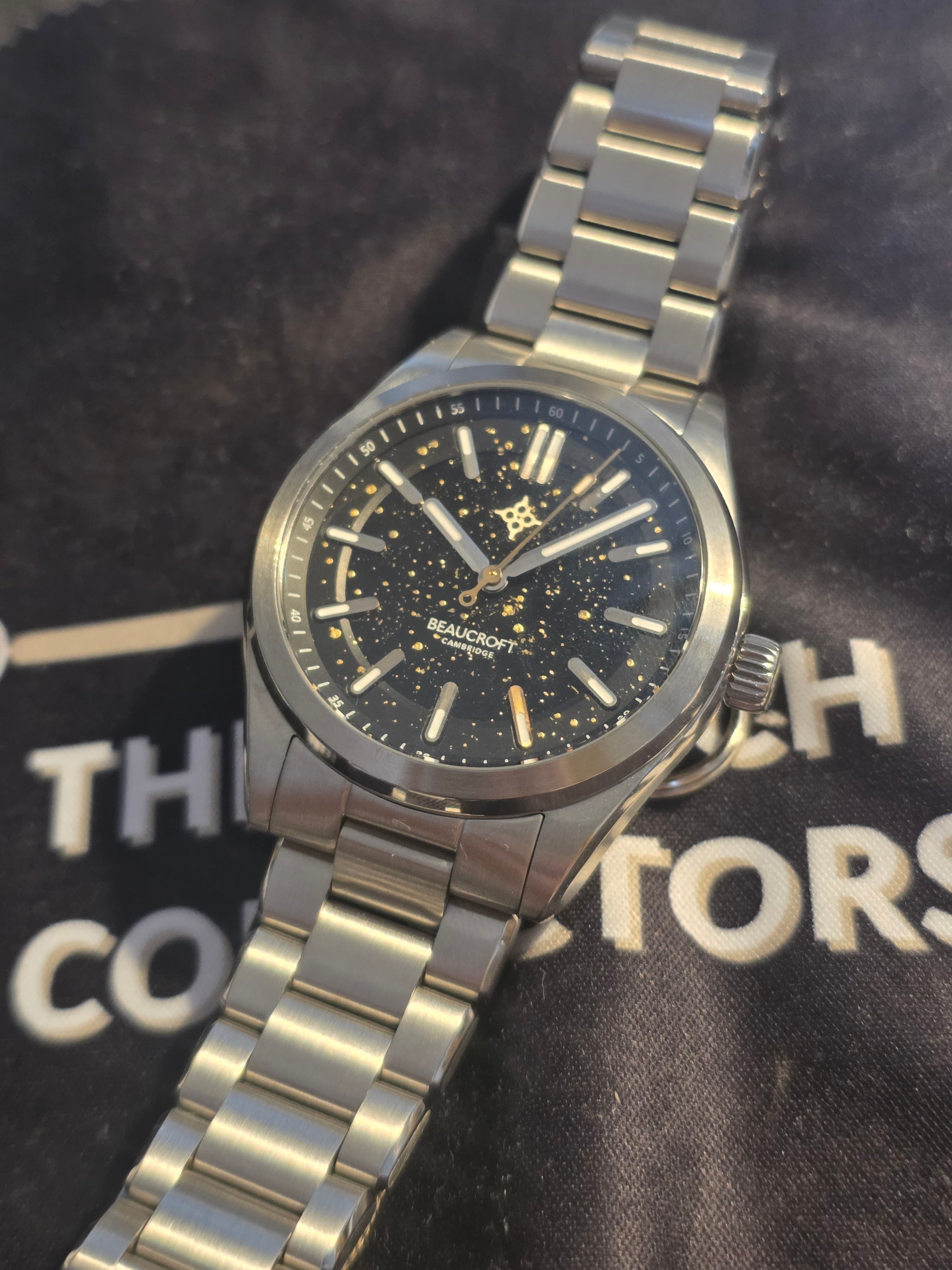 the watch collectors club beaucroft element obsidian special edition with clack dial with gold flecks gold second hands and five index and steel case and bracelet