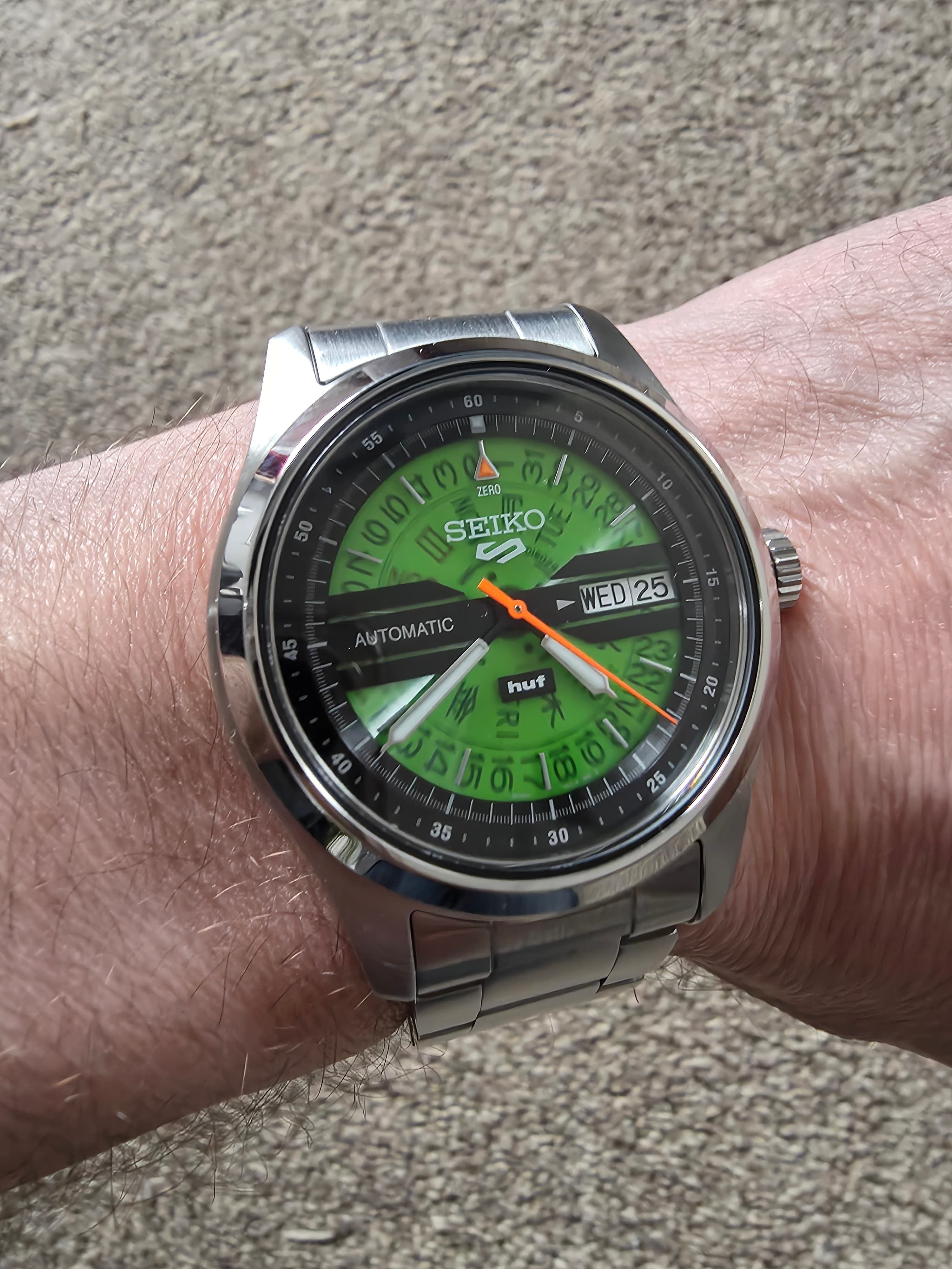 the seiko huf collab with green see throuhg dial, day date function oragne second hand and steel case