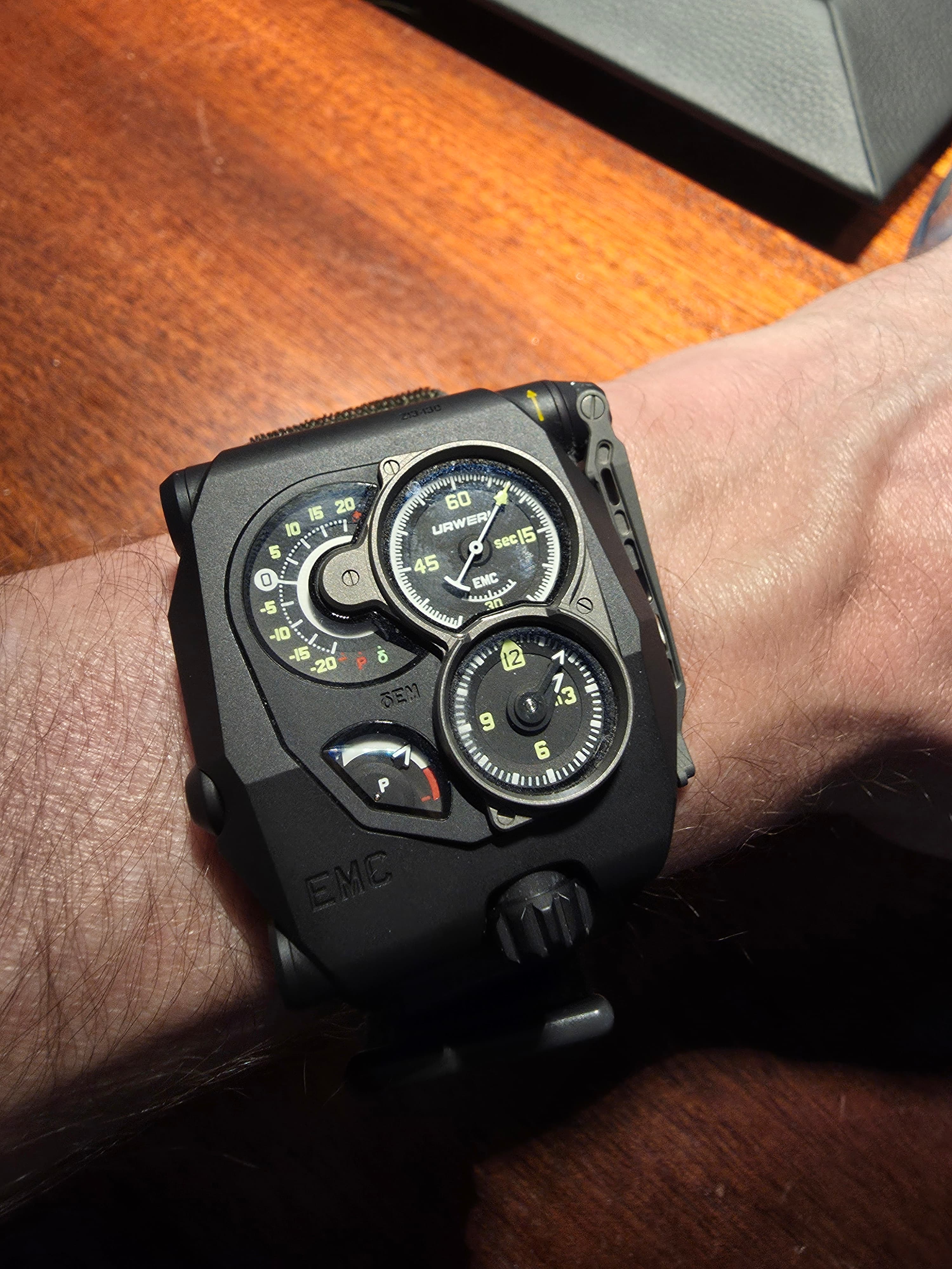 a large black Urwerk EMC watch with three dia;s all in black with strong lume and an angled case with long lever on the right hand side