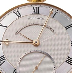 a close up of a large pocket watch with white gold dial, roman numerals, gold hands, a power reserve and elegant small seconds display below